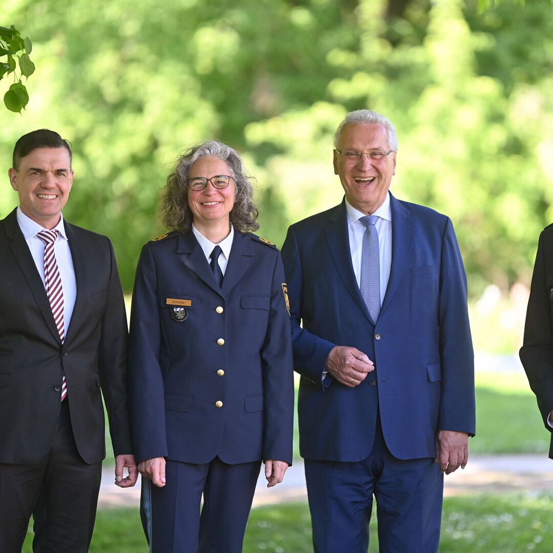 Gruppenbild (von links nach rechts:) Dirk Schmidt, neuer Polizeivizepräsident PP Oberbayern Nord, Kerstin Schaller, neue Polizeipräsidentin PP Oberbayern Nord, Innenminister Joachim Herrmann, Günther Gietl Polizeipräsident Oberbayern Nord a.D. im Hintergrund grüne Bäume