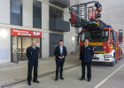 Staatssekretär Sandro Kirchner  zwischen zwei Personen der Feuerwehrschule, im Hintergrund Feuerwehrauto während Übung