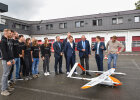 Innenminister Joachim Herrmann und weitere Personen, u.a. Vertreter des Pilotprojekts stehen vor Feuerwehrgebäude um die Drohne herum