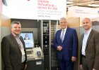 Herrmann und zwei Vertreter der Messe neben ausgestelltem Bankautomaten