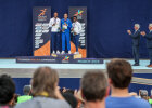 Drei Athleten auf Siegertreppchen, Herrmann neben weiteren rechts applaudierend