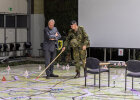 Mann in Bundeswehrkleidung zeigt präsentiert Herrmann eine große Karte auf dem Boden mit einem Stab