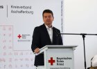 Auf dem Bild ist Staatssekretär Sandro Kirchner bei seiner Rede anlässlich der Einweihung der neuen Rettungswache des Kreisverbandes Aschaffenburg des Bayerischen Roten Kreuzes zu sehen.