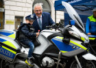 Innenminister Joachim Herrmann neben Kind in Polizeiweste und -hut auf Polizeimotorrad