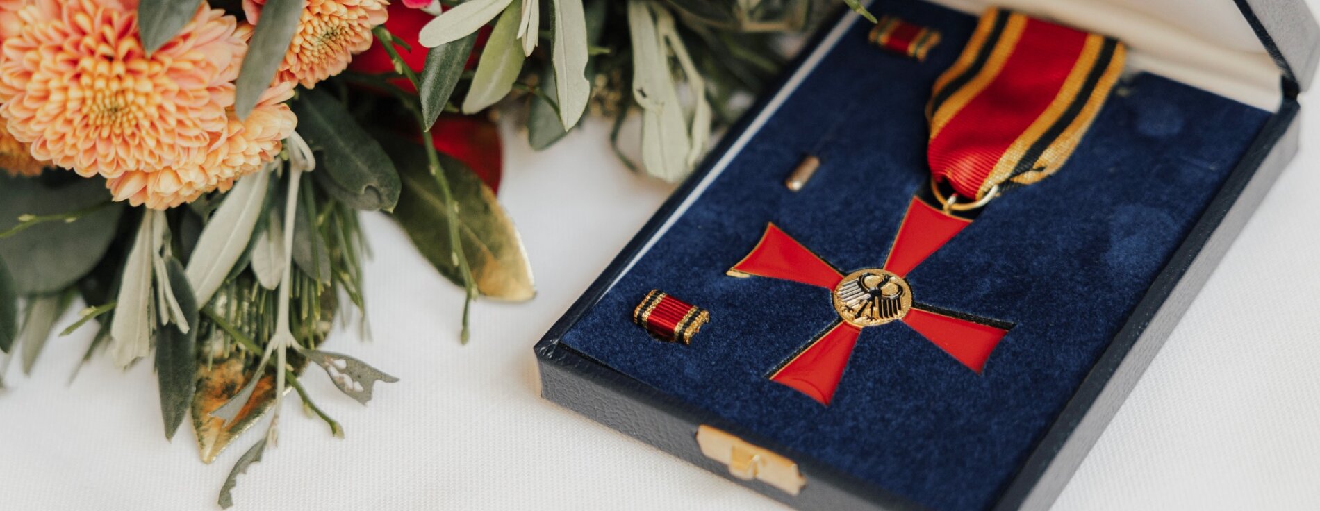 Verdienstkreuz am Bande des Verdienstordens der Bundesrepublik Deutschland Bundesverdienstkreuz in Schachtel und Blumenstrauß