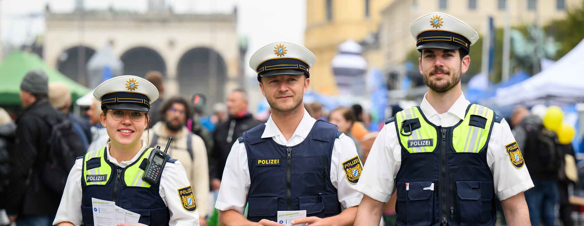 3 Polizistinnen und Polizisten auf Festival, im Hintergrund Festivalbesucher