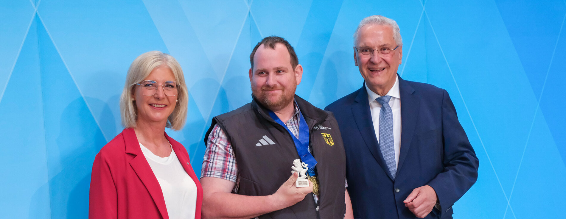 30. April 2025: Im Kuppelsaal der Staatskanzlei würdigt Bayerns Innen- und Sportminister Joachim Herrmann die bayerischen Athletinnen und Athleten der Special Olympics World Winter Games 2025 – für ihre beeindruckende Leistung, gelebte Inklusion und den Einsatz für olympische Werte. (Links) Staatsministerin für Familie, Arbeit und Soziales Ulrike Scharf, (Mitte) Thomas Linser Snowboarderathlet, (rechts) Innenminister Joachim Herrmann
