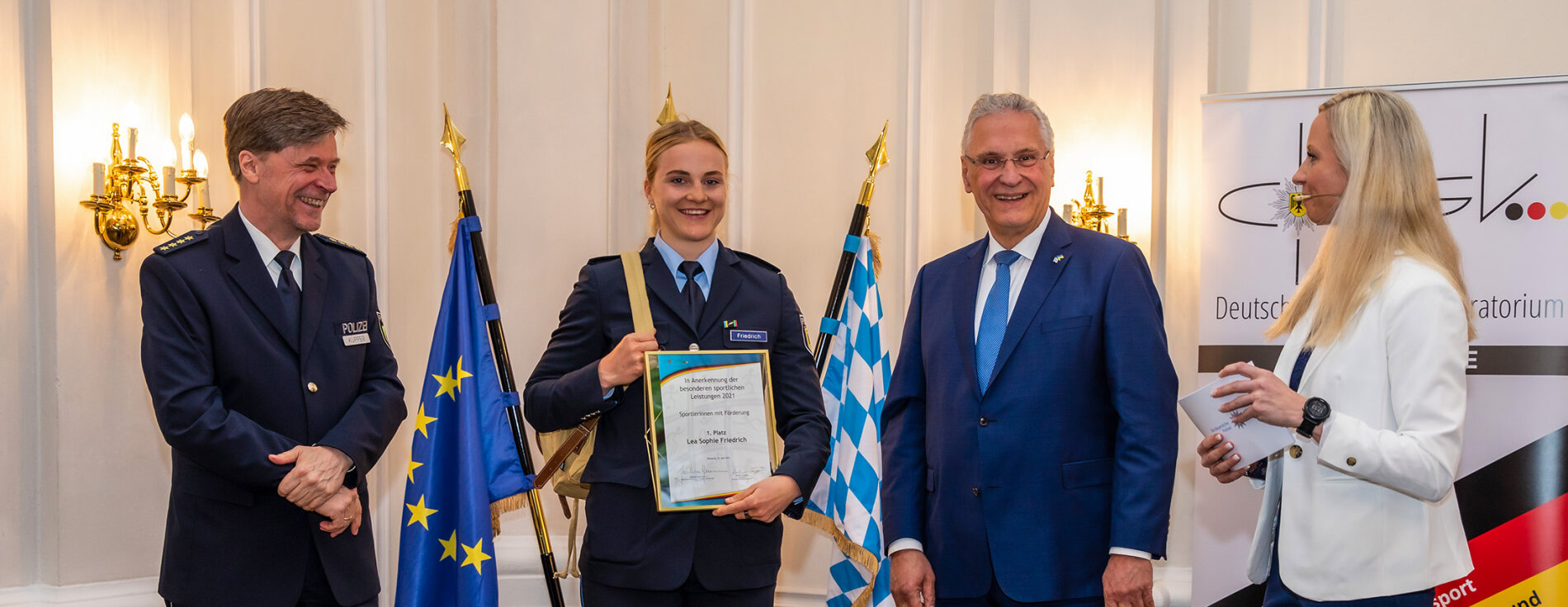 25. April 2022: Innenminister Joachim Herrmann ehrt Polizeisportlerinnen und Polizeisportler: In einer feierlichen Veranstaltung wurden insgesamt 16 Polizeisportlerinnen und Polizeisportler des Bundes und der Länder geehrt. „Mit Ihren herausragenden sportlichen Leistungen haben Sie das Ansehen der Polizei in besonderer Weise gefördert“, lobte Herrmann. Innenminister Joachim Herrmann neben Lea Sophie Friedrich mit Urkunde, Vertreter des DPSK und Moderatorin