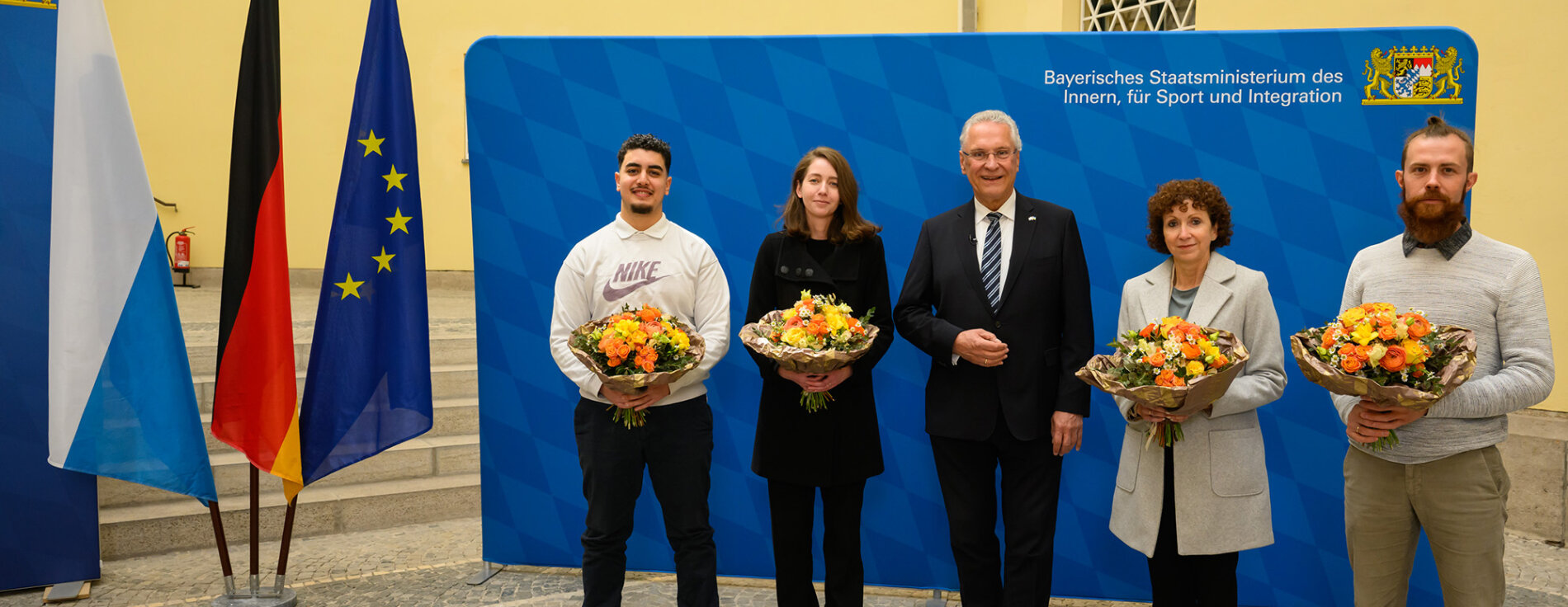 22. April 2022: Innenminister Joachim Herrmann hat heute die Einbürgerungsstatistik 2021 vorgestellt und im Anschluss vier Personen die Einbürgerungsurkunde überreicht. „Die Einbürgerungen sind ein starkes Zeichen erfolgreicher Integration. Nun stehen den Eingebürgerten auch politisch viele Möglichkeiten offen, unsere Gesellschaft mitzugestalten“, sagte Herrmann. Gruppenfoto mit Innenminister Joachim Herrmann und den vier Eingebürgerten mit Blumensträußen