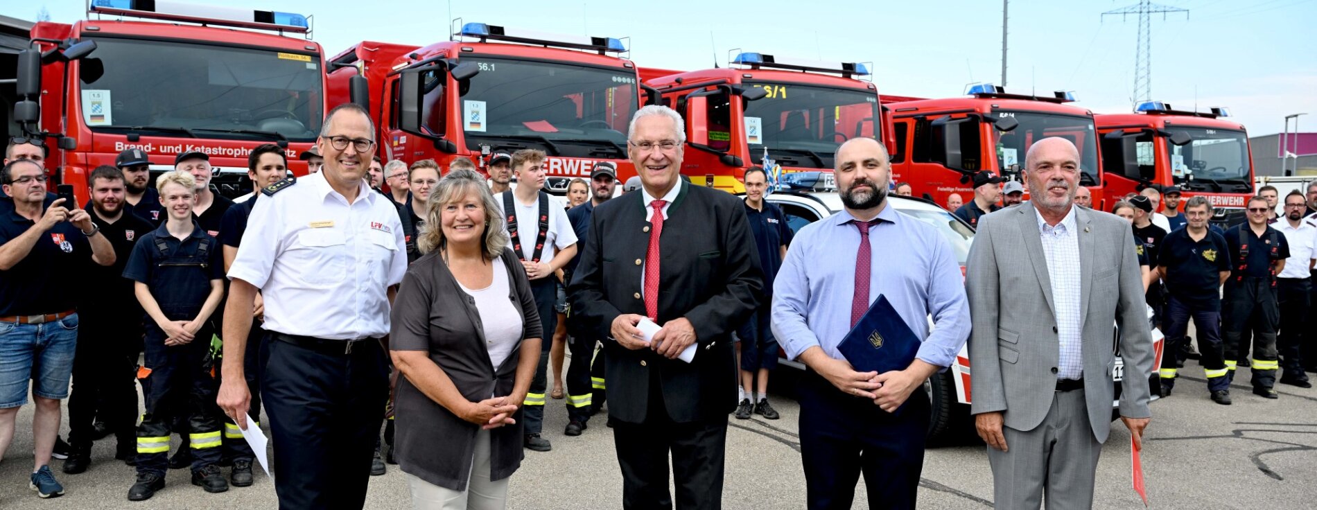 14. August 2024: Innenminister Joachim Herrmann hat heute einen weiteren großen Hilfskonvoi für die ukrainische Feuerwehr verabschiedet. Die dringend benötigte Ausrüstung und die Einsatzfahrzeuge sollen dazu beitragen, die Sicherheit der Zivilbevölkerung in der Ukraine zu erhöhen. "Wir stehen an der Seite der Ukraine und unterstützen sie weiterhin nach Kräften", betonte Herrmann. Innenminister Joachim Herrmann, ukrainischer Generalkonsul Oleksii Kravets und der Vorsitzender des Landesfeuerwehrverbandes Bayern (LFV) Johann Eitzenberger mit weiteren vor einer Gruppe Helferinnen und Helfern und Feuerwehrfahrzeuge