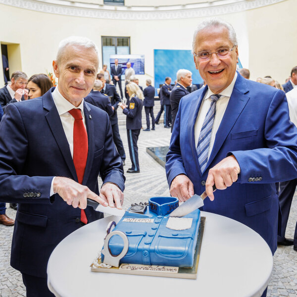 INTERPOL-Generalsekretär Prof. Dr. Jürgen Stock und Innenminister Joachim Herrmann schneiden Kuchen in Polizeiuniform an