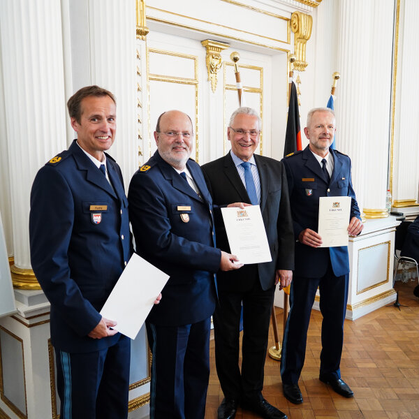 Fuchs, Zink, Herrmann und Schöniger mit Urkunden in festlichem Saal