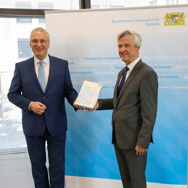 Innenminister Joachim Herrmann mit statistischem Jahrbuch in der Hand und Präsident des Landesamts für Statistik Dr. Thomas Gößl