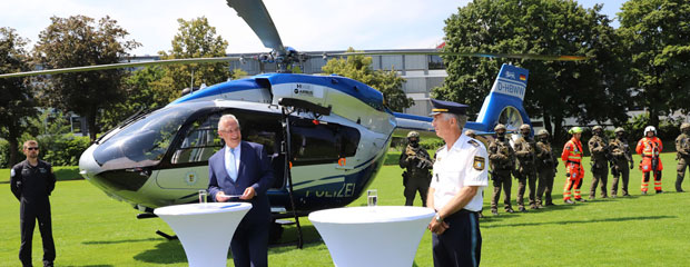 Innenminister Herrmann mit EInsatzkräften vor einem Polizeihubschrauber