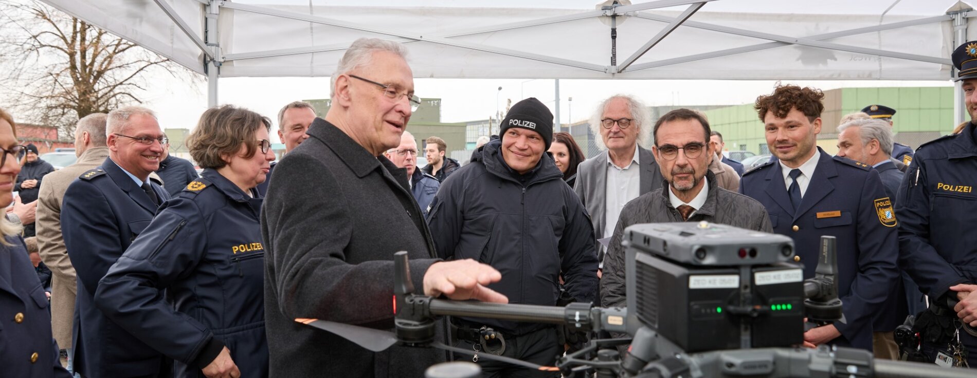 10. März 2025: Innenminister Joachim Herrmann stellt die neue Grenzpolizeiinspektion am Flughafen Memmingen vor. Innenminister Herrmann bei Präsentation mit vielen Menschen, im Vordergrund eine Drohne