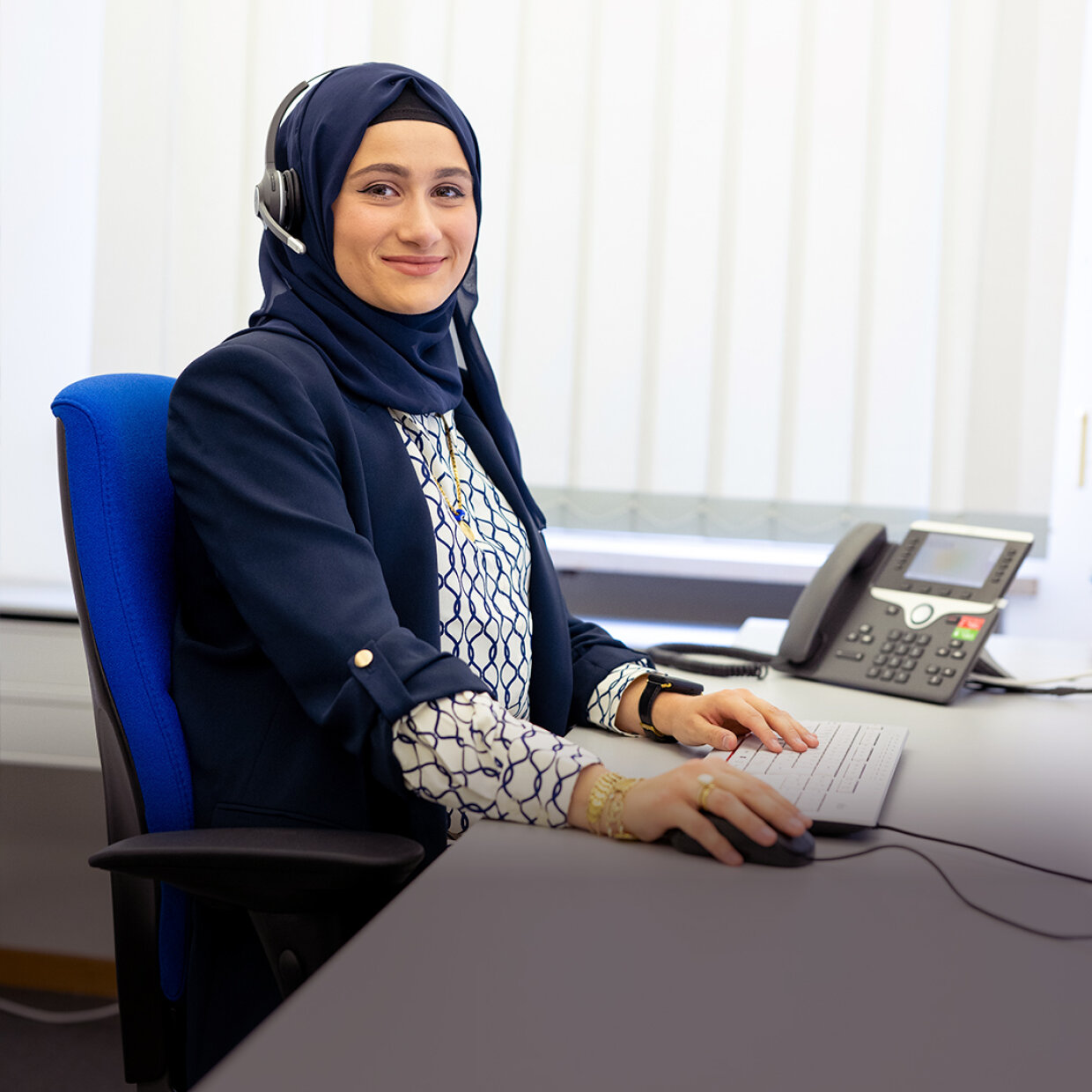 Frau mit Headset an Schreibtisch mit Computer