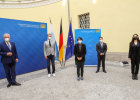 Innenminister Herrmann bei Pressekonferenz neben vier Eingebürgerten