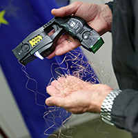 11. November 2020: Innenminister Joachim Herrmann hat heute im Innenausschuss des Bayerischen Landtags seine Planungen für zusätzliche Distanz-Elektroimpulsgeräte (DEIG), früher landläufig als "Taser" bezeichnet, bei der Bayerischen Polizei vorgestellt. "Die Praxiserfahrungen haben gezeigt, dass das DEIG bei bestimmten Einsatzlagen eine wertvolle Ergänzung der polizeilichen Einsatzmittel sein kann", erklärte Herrmann. "Deshalb werden wir alle Unterstützungskommandos sowie alle 'geschlossenen Einsatzeinheiten' der Landespolizei mit dem DEIG ausstatten." Distanz-Elektroimpulsgerät in der Hand