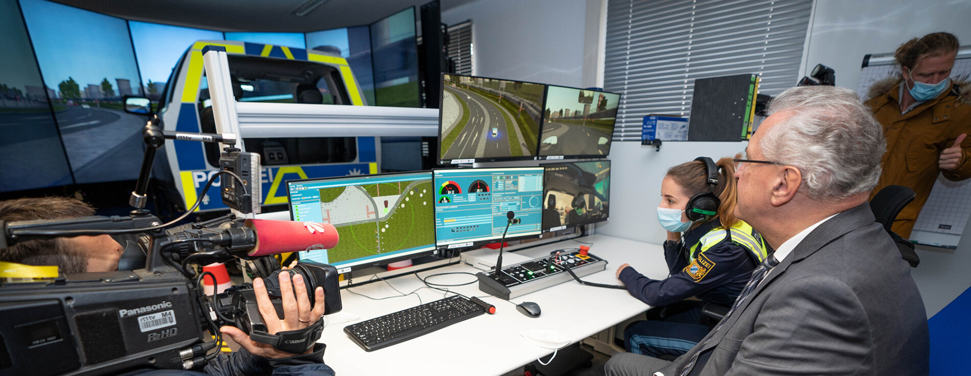 Mit den Fahrsimulatoren können Polizeischüler gefahrlos realitätsnahe Einsatzfahrten üben. Innenminister Joachim Herrmann vor Monitore mit Fahrsimulation, im Hintergrund Polizeisimulator