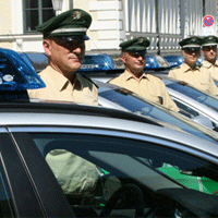 Polizisten neben Polizeiautos