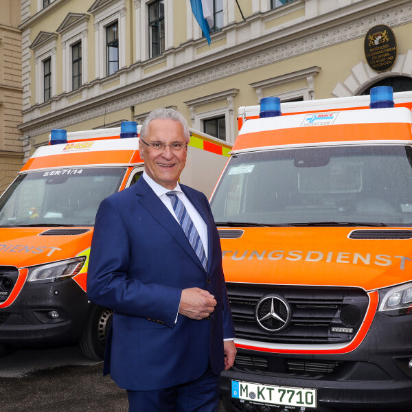 Innenminister Joachim Herrmann vor Rettungsdienst-Fahrzeugen vor dem Innenministerium