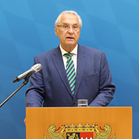 München, 30. September 2020 (stmi). Bayerns Innenminister Joachim Herrmann und Dr. Burkhard Körner, Präsident des Bayerischen Landesamts für Verfassungsschutz (LfV), haben heute die Neuauflage der Broschüre „Das System Scientology“ und den Kurzfilm "10 Tipps wie du dich nicht verarschen lässt – diesmal von Scientologen“ vorgestellt. „Die lautlose Gefahr, die von Scientology ausgeht, gerät angesichts anderer gravierender Bedrohungen leicht in Vergessenheit. Umso wichtiger ist es, dass mit diesen beiden Formaten die Aufklärung der Öffentlichkeit weiter verstärkt wird“ sagte Herrmann. Innenminister Herrmann und LfV-Präsident Dr. Burkhard Körner hinter Rednerpult