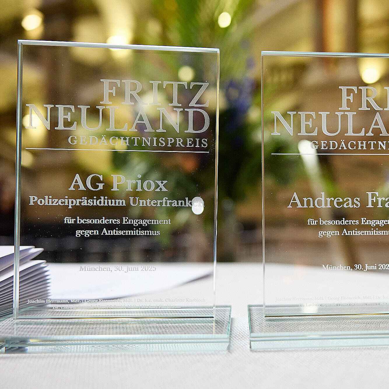 zwei gläserne Preisgegenstände mit Inschrift zum Fritz-Neuland-Gedächtnispreis auf einem Stehtisch