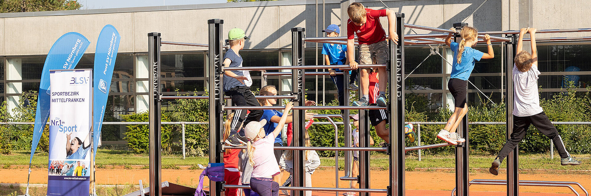 Kinder am Klettergerüst spielend und kletternd auf dem Sportplatz