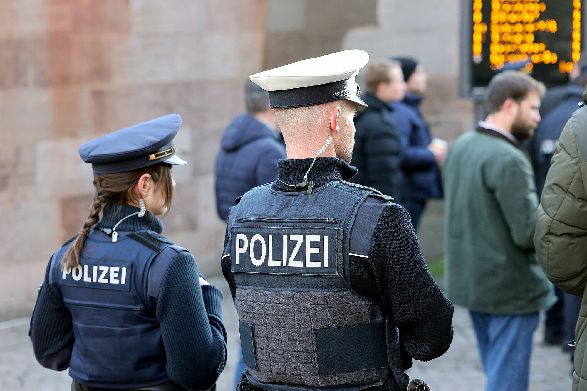 Eine Polizistin und ein Polizist von hinten bei einem Streifendienst auf einem Bahnhof