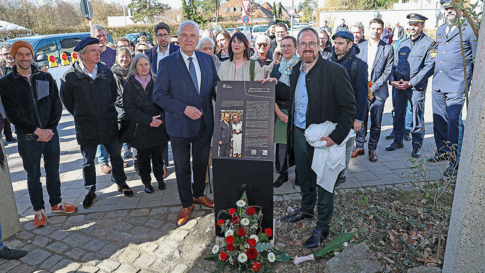 Eine Gruppe von Menschen steht um eine Tafel, die Informationen oder Ehrungen präsentiert.