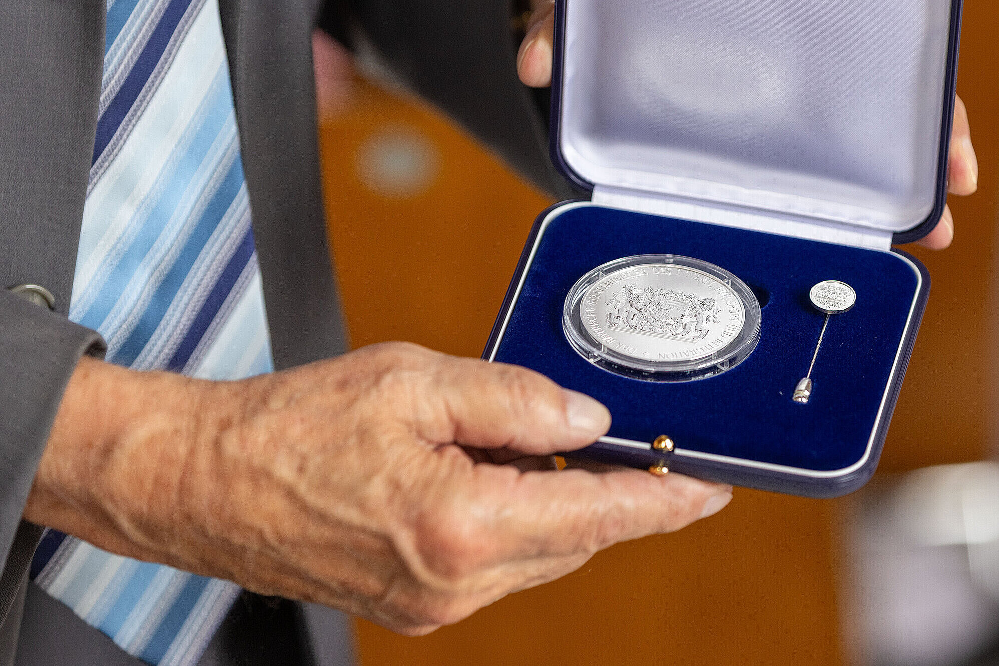 Hände halten die geöffnete Schatulle mit der Kommunalen Verdienstmedaille in Silber