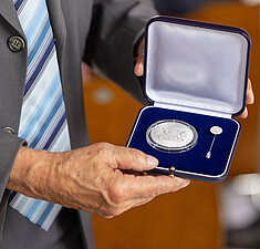Hände halten die geöffnete Schatulle mit der Kommunalen Verdienstmedaille in Silber