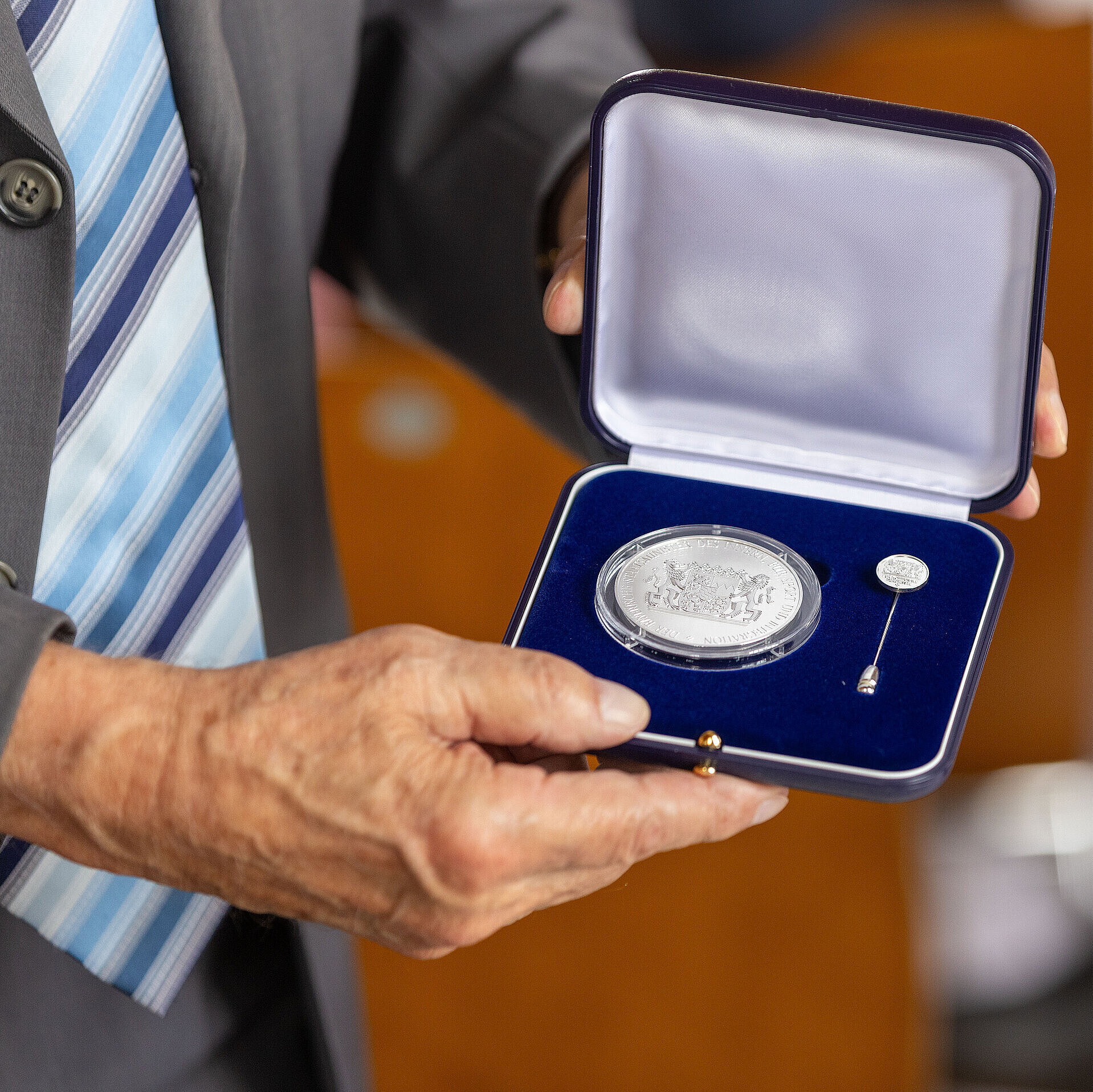 Hände halten die geöffnete Schatulle mit der Kommunalen Verdienstmedaille in Silber