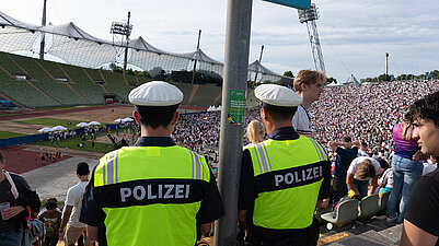 zwei Polizisten von hinten mit Blick in das Olympiastadion 