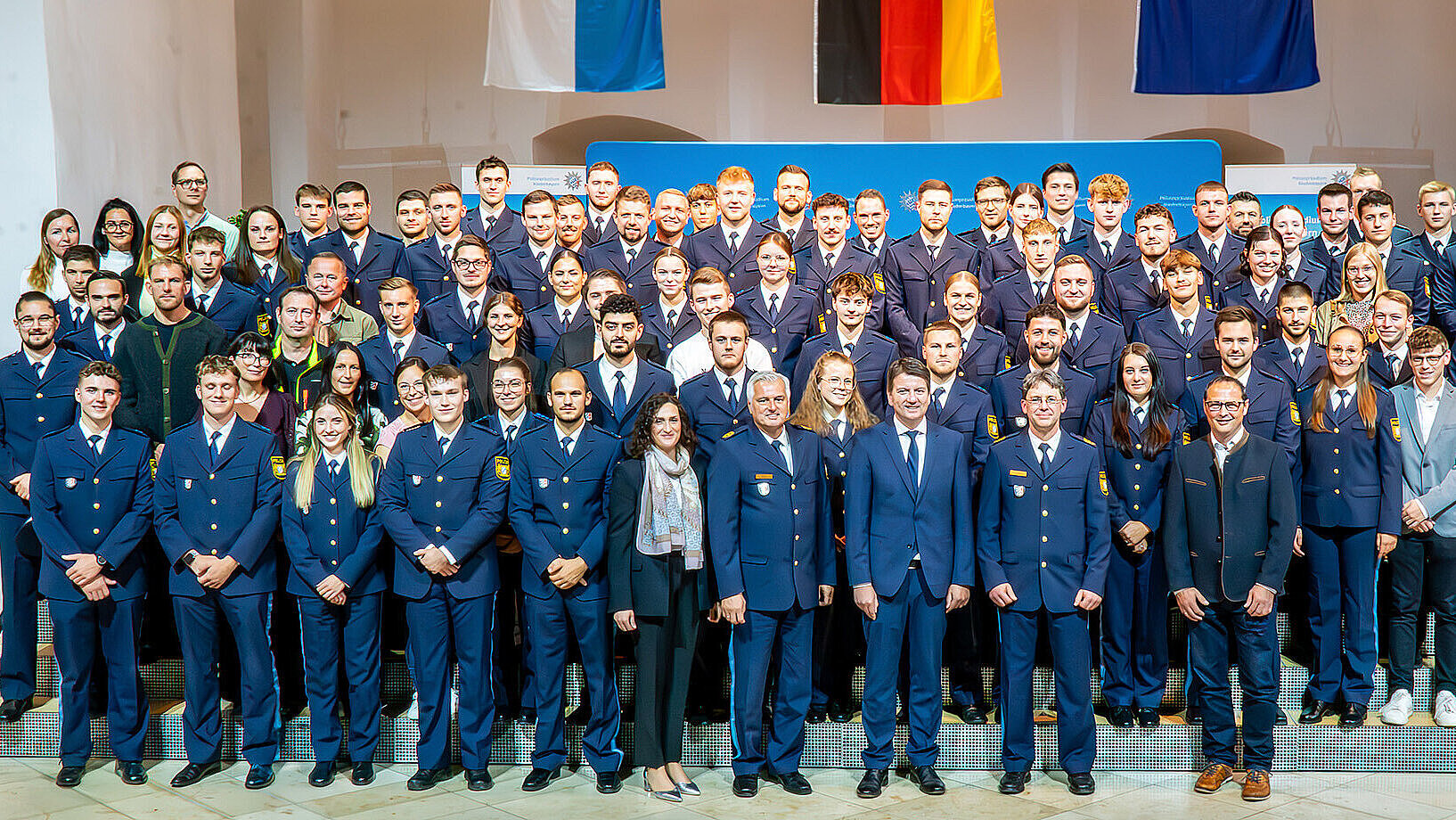 Gruppenbild mit allen neu eingestellten Polizeibeamtinnen und -beamten sowie Staatssekretär Sandro Kirchner in der Mitte des Bildes.