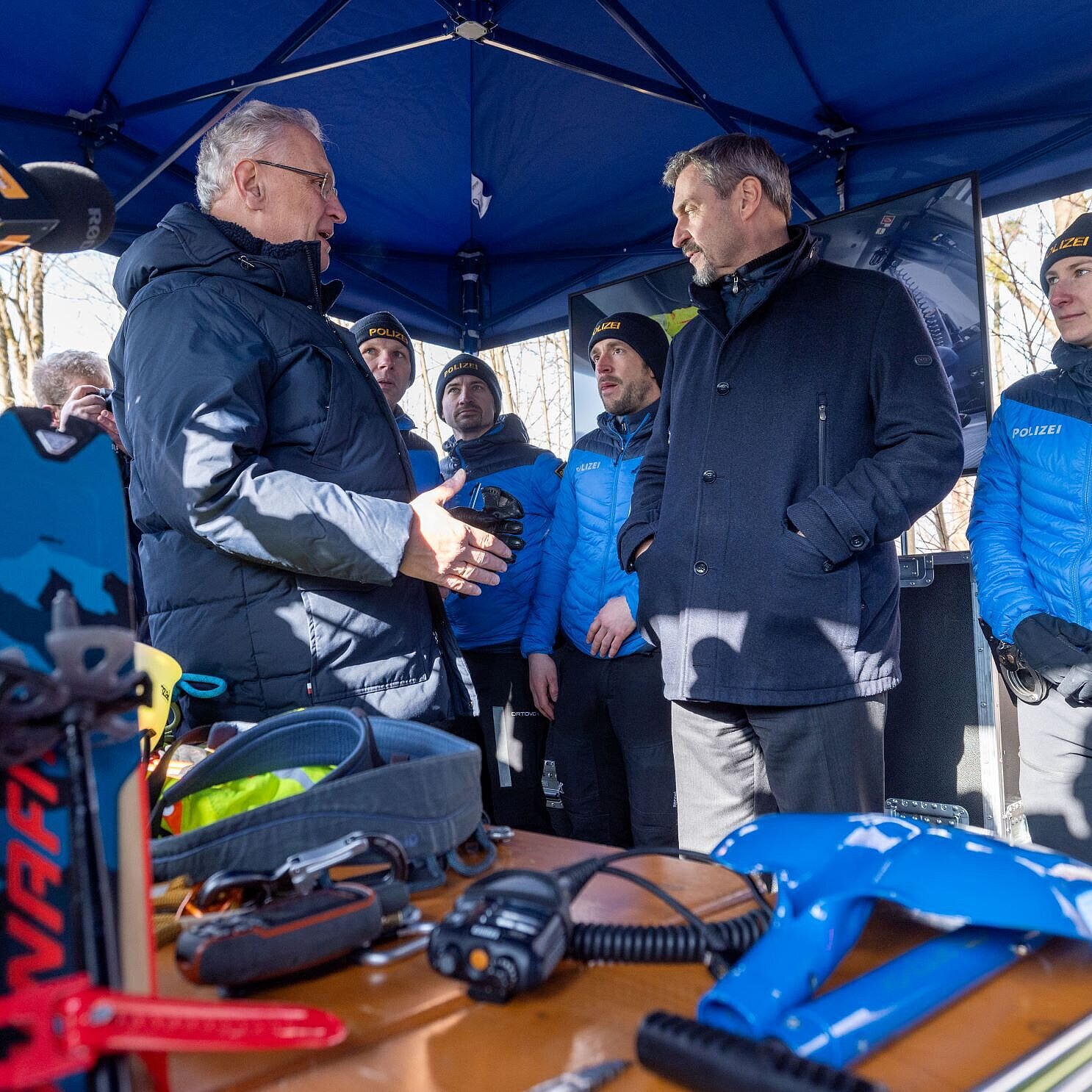 Auf dem Bild sind Innenminister Joachim Herrmann, Ministerpräsident Dr. Markus Söder und einige Polizistinnen und Polizisten zu sehen, die Ausrüstungsgegenstände der Polizei begutachten.