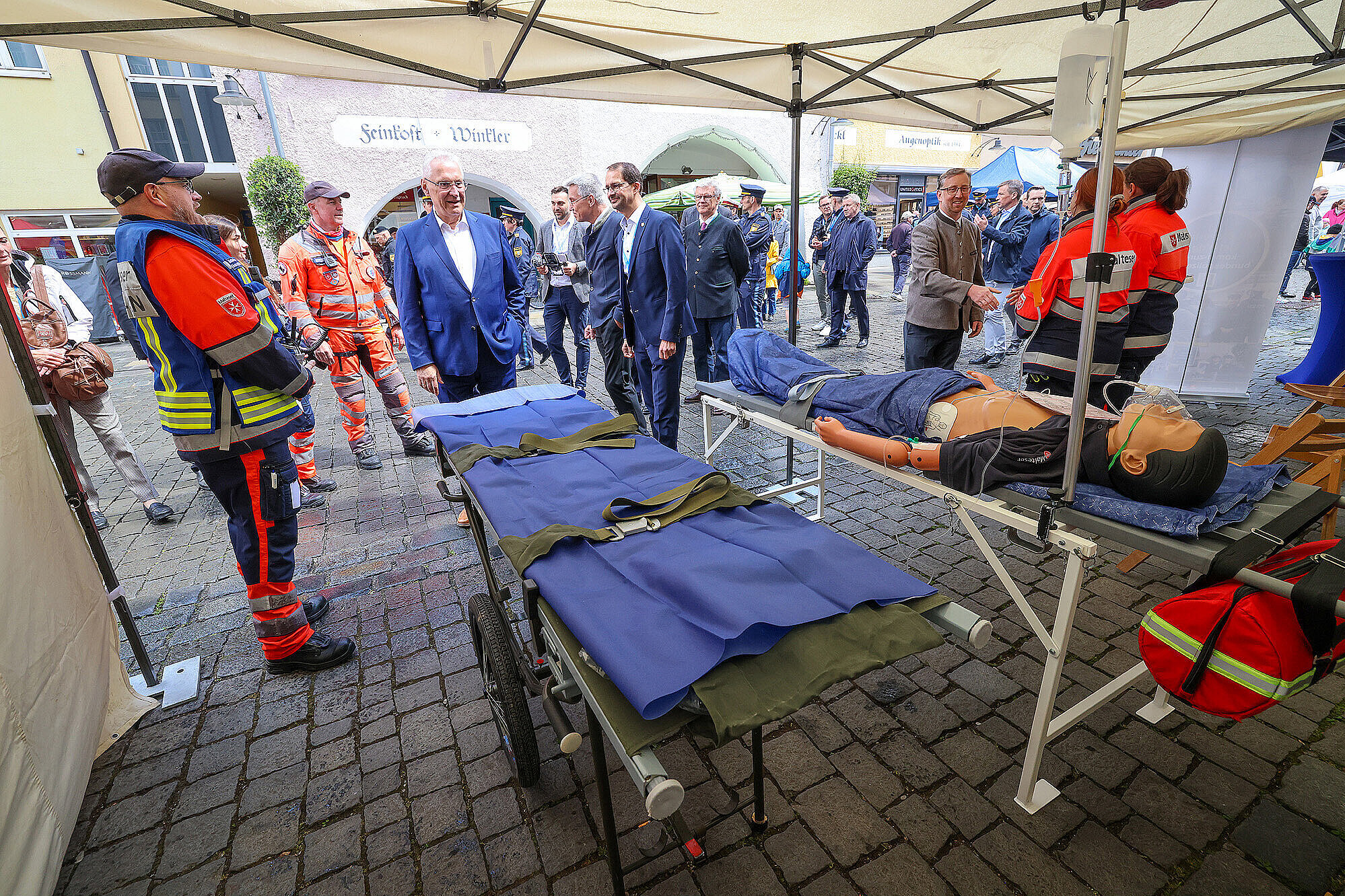 Innenminister Herrmann steht vor einer Trage des Deutschen Roten Kreuzes, die beim Landestag der Verkehrssicherheit in Rosenheim am 17.05.25 Aussteller und Teilnehmer waren.