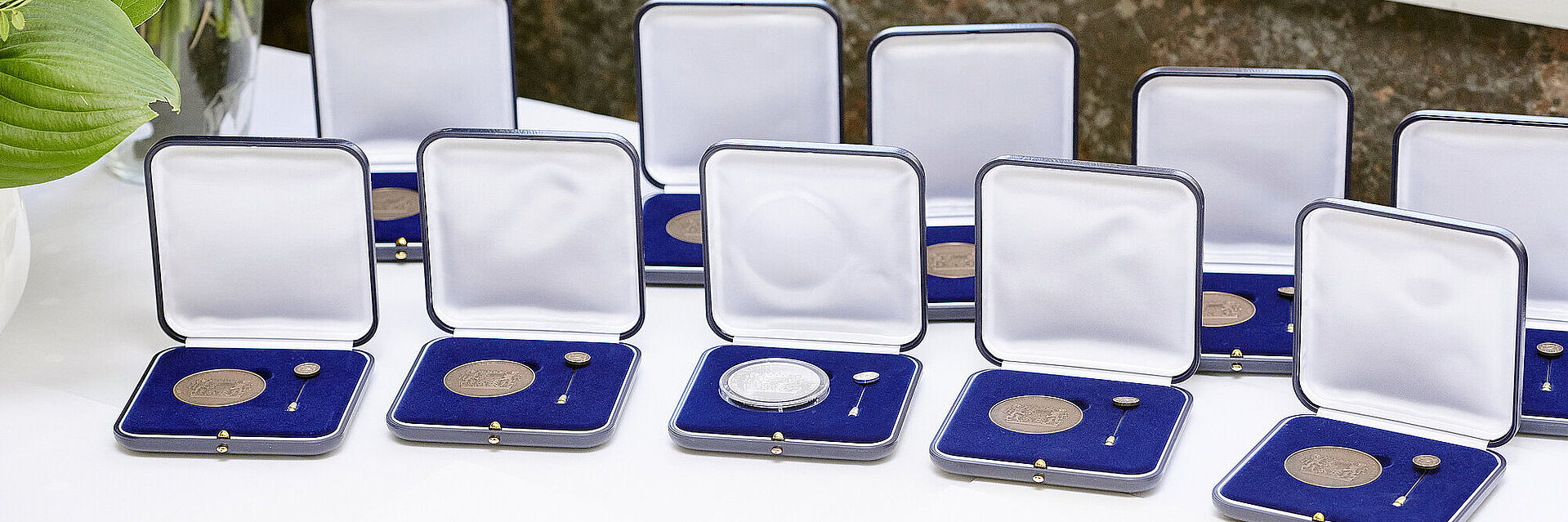 Mehrere Kommunale Verdienstmedaillien in Bronze und Silber im Etui aufgereiht auf einem Tisch