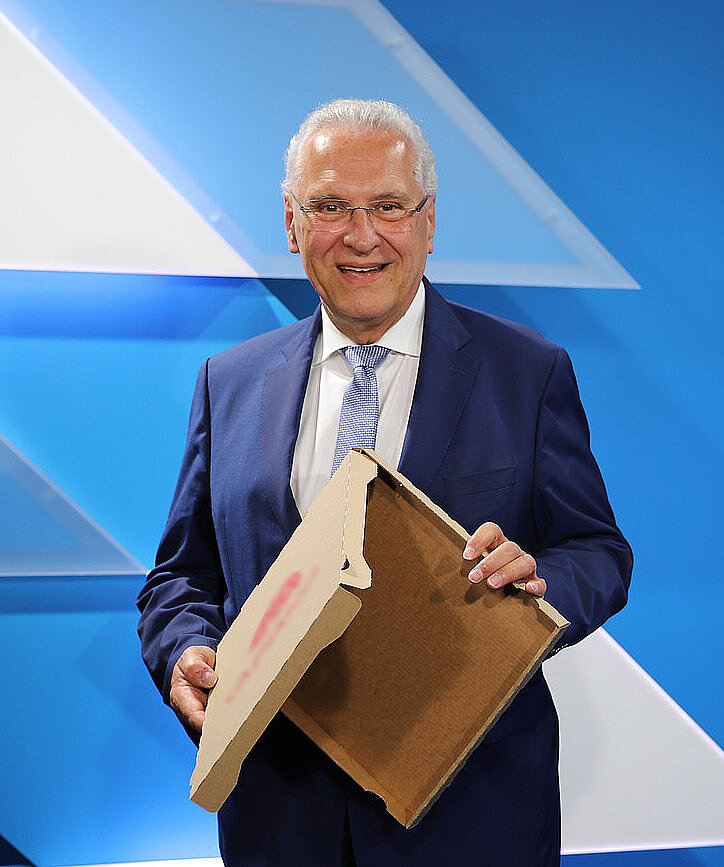 Innenminister Joachim Herrmann hält einen leeren Pizzakarton