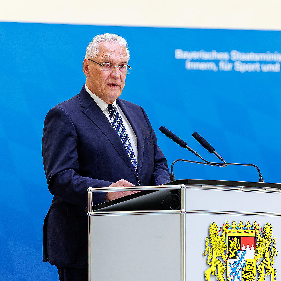 Innenminister Joachim Herrmann am Rednerpult vor Pressewand