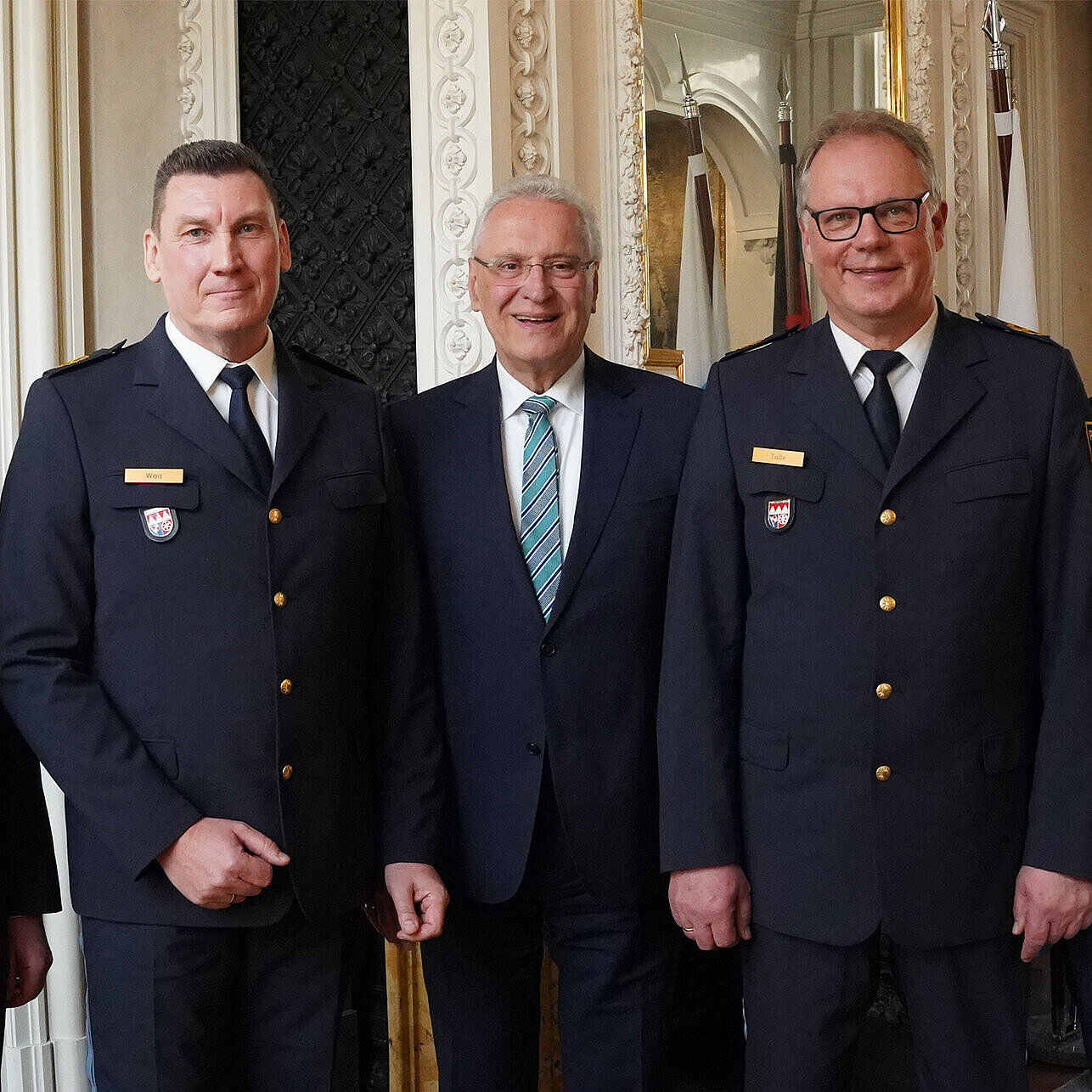 Fünf Männer in einer Reihe, drei davon mit Polizeiuniform