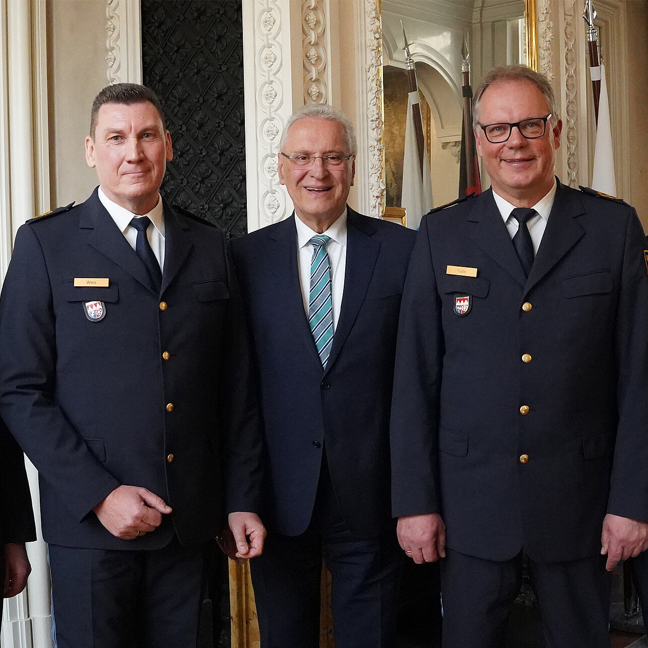 Fünf Männer in einer Reihe, drei davon mit Polizeiuniform