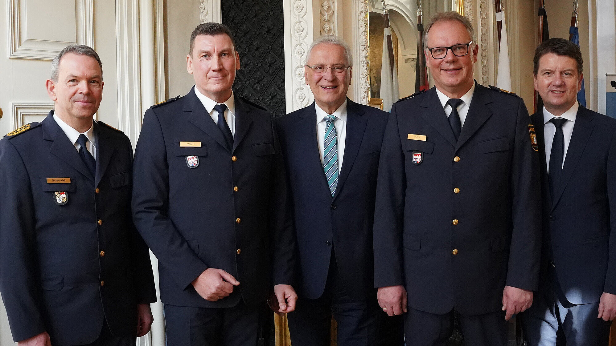 Fünf Männer in einer Reihe, drei davon mit Polizeiuniform