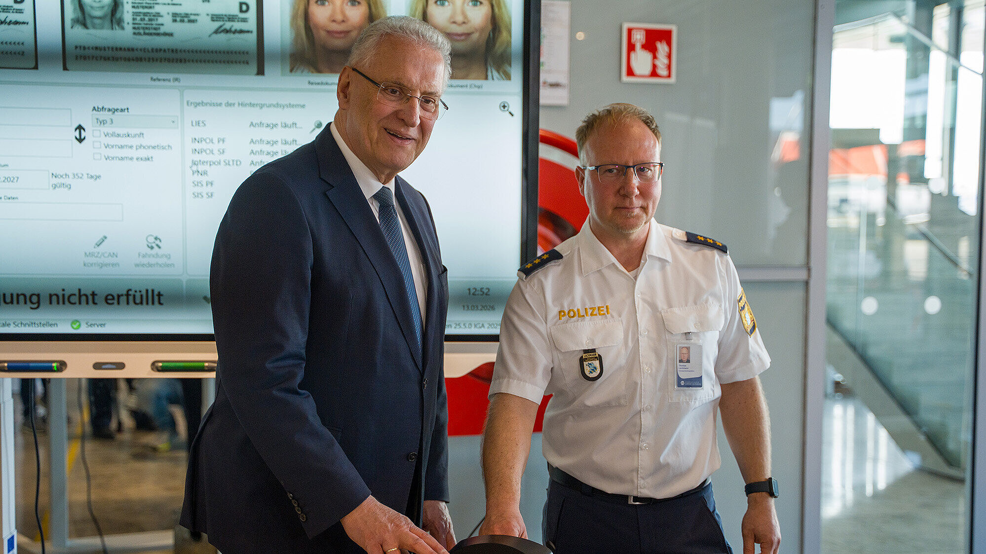 Zwei Männer in Anzügen stehen neben einem Laptop und scheinen eine Präsentation zu besprechen.