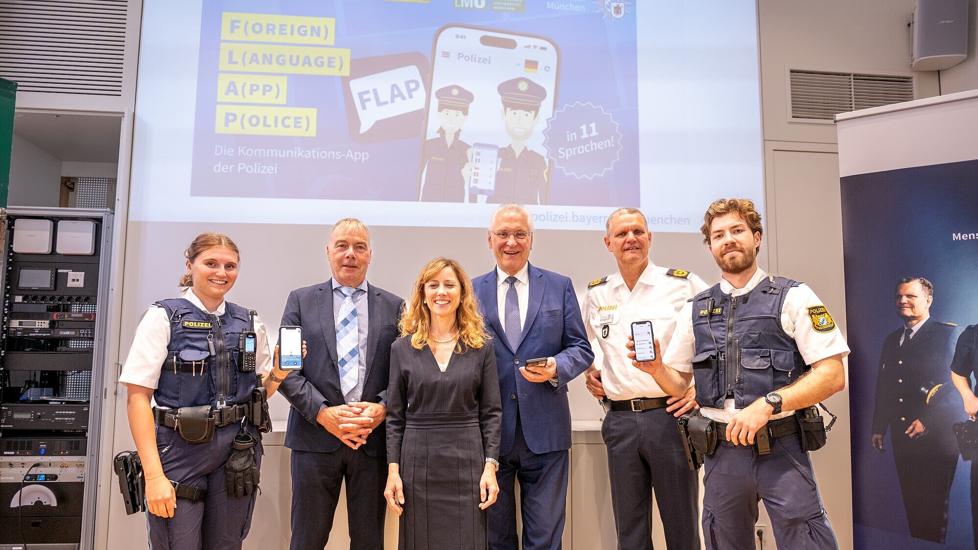 Gruppenbild mit Herrmann und weiteren Personen, u.a. Polizisten, vor Präsentation mit Handyapp