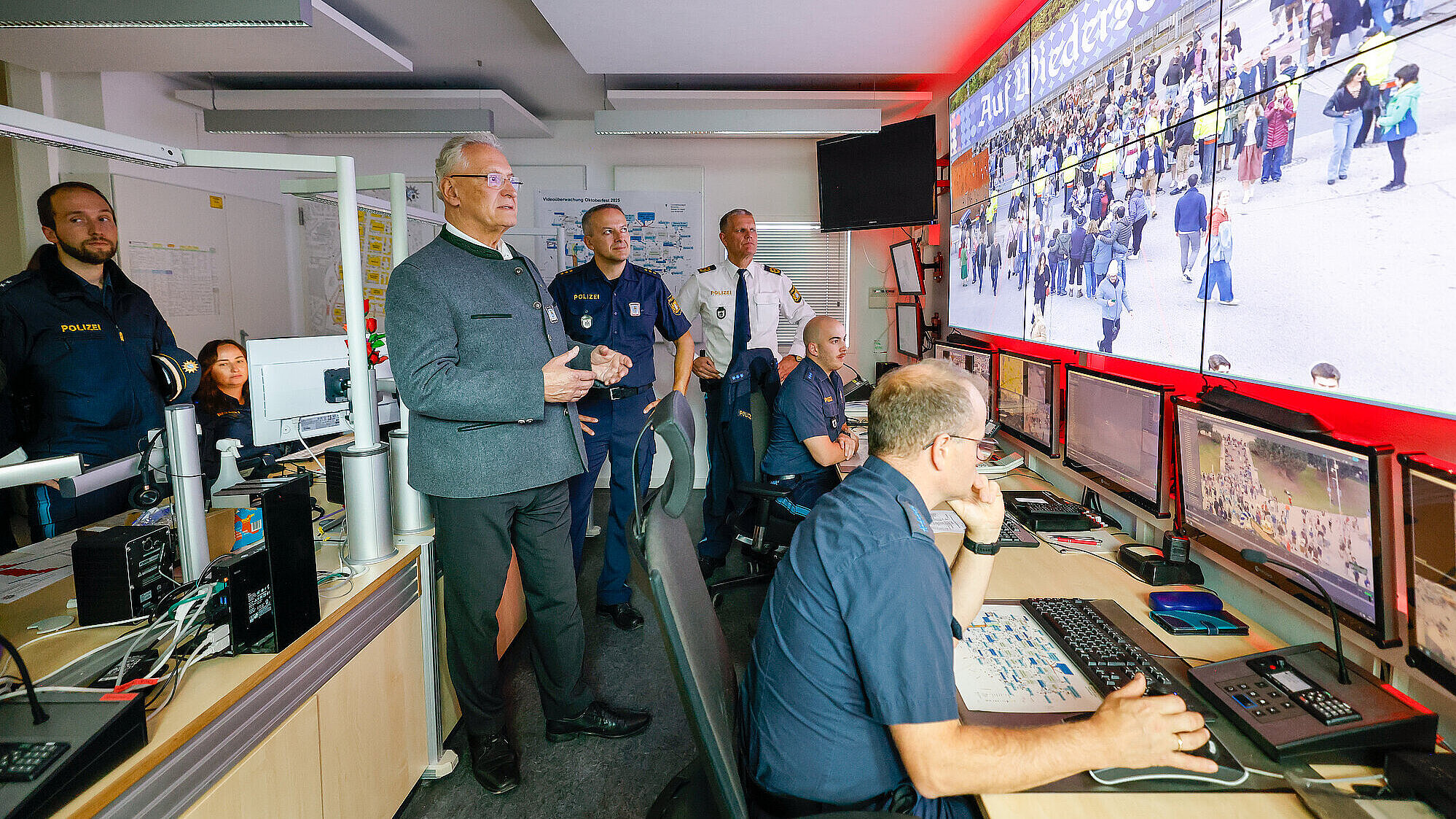 Innenminister Joachim Herrmann lässt sich von Polizisten die Videoüberwachung an großem Bildschirm zeigen