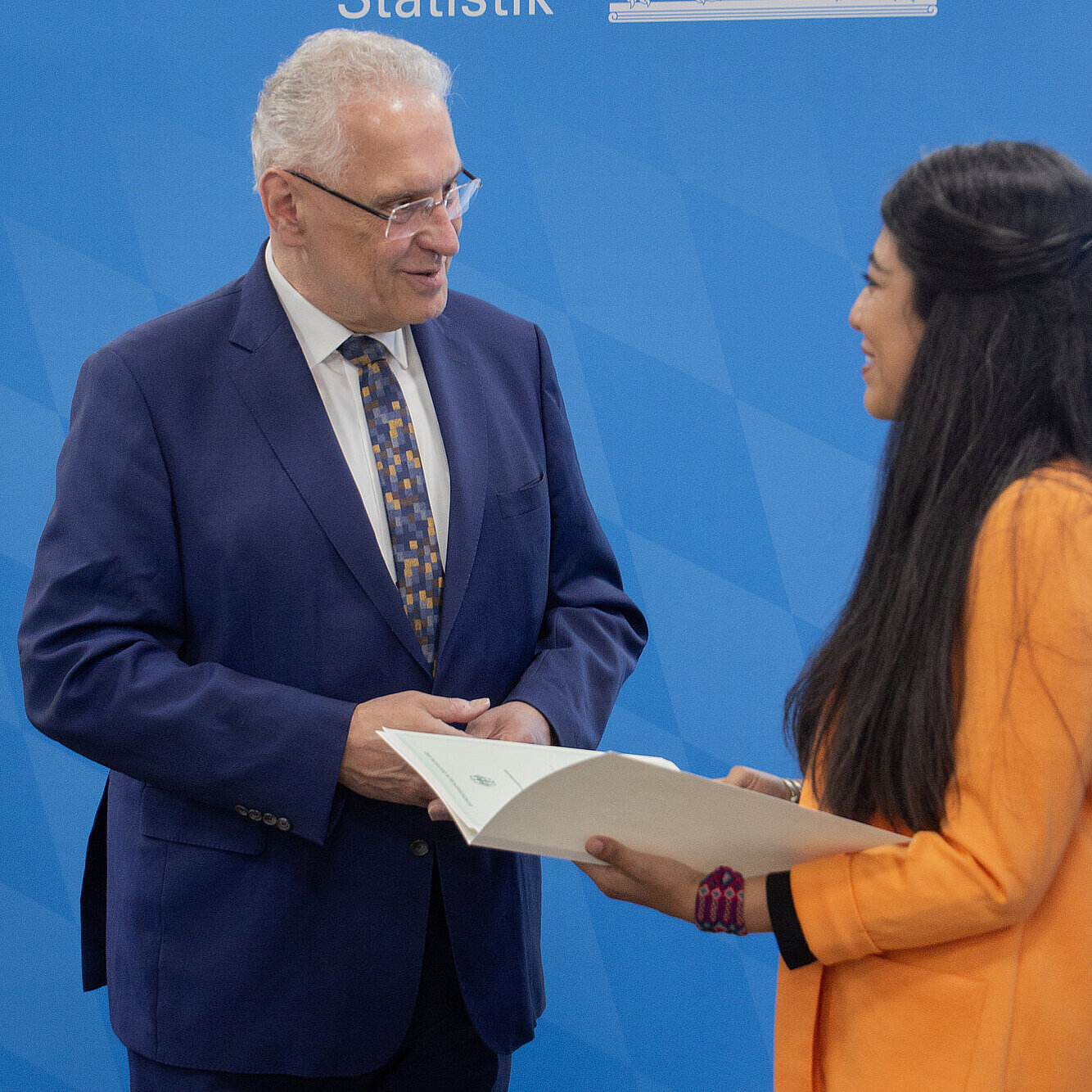 Innenminister Herrmann blickt zu einer Frau mit Urkunde in der Hand