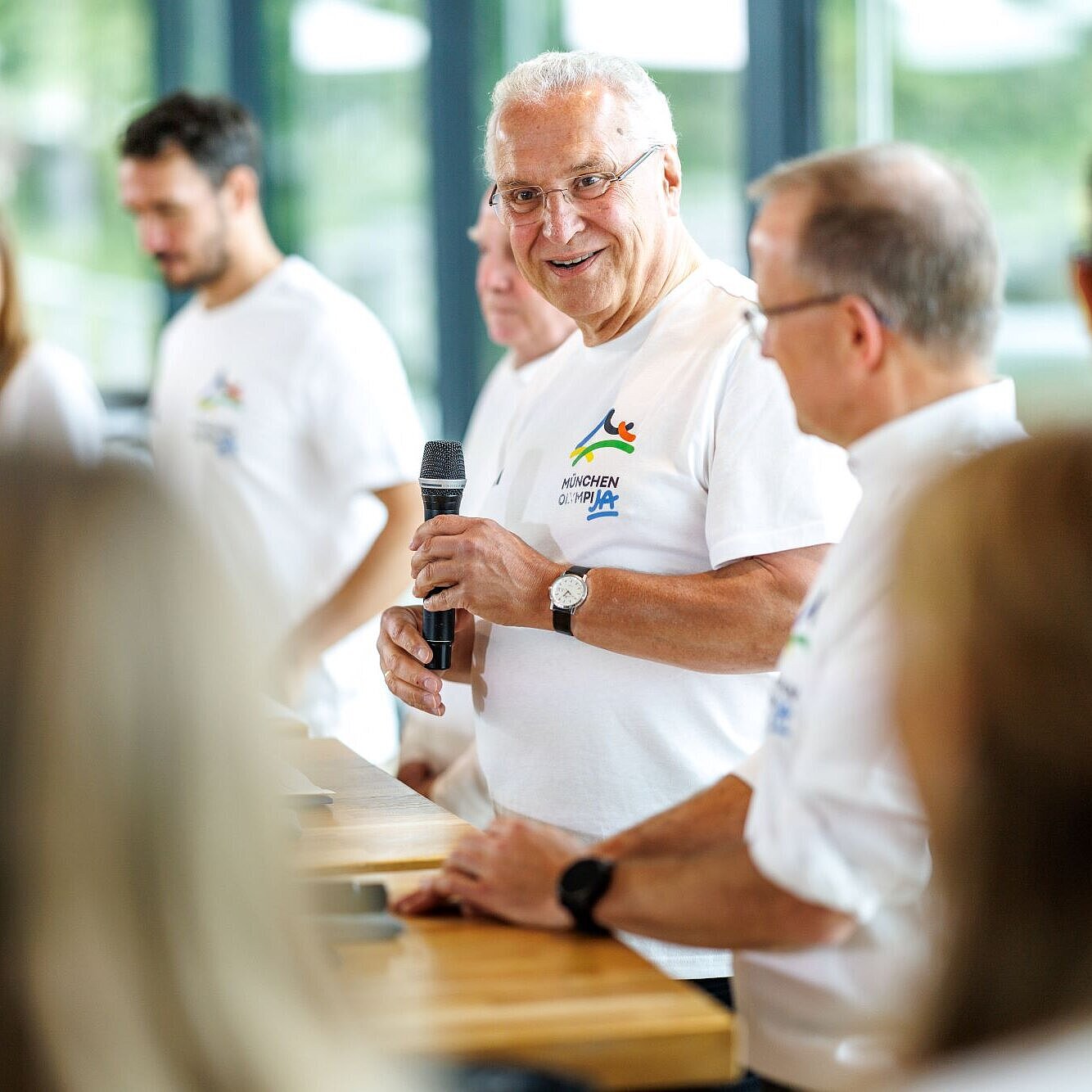 Auf dem Bild ist Innen- und Sportminister bei seiner Rede während der Pressekonferenz zu sehen. Neben ihm zahlreiche Sportlerinnen und Sportler sowie BLSV-Präsident Jörg Ammon.