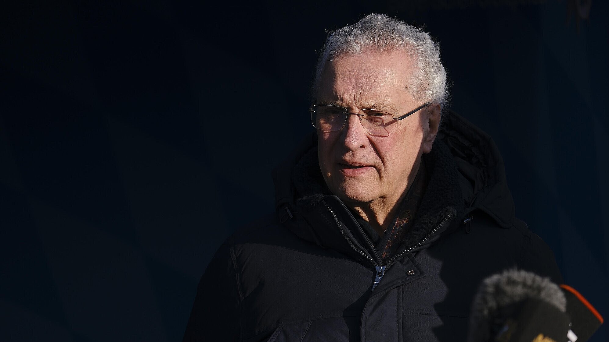 Herrmann im Dunklen vor Mikrofon, ernst blickend