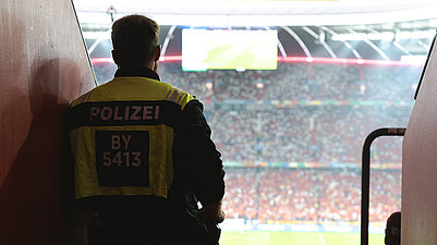 Polizist von hinten mit Blick auf ein Fußballspiel in der Allianzarena